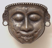 Unknown (India, Malabar Coast) / 
      Demon (Bhuta) Mask, 19th century / 
      bronze with silver admixture / 
      7 5/8 x 8 3/8 x 3 1/2 in. (19.4 x 21.3 x 8.9 cm) / 
        / 
      The three masks on view in this exhibition, depict
      demons, or <em>Bhutas</em>, and were worn by Tulu devotees associated
      with the cult of the Mother Goddess. Danced reenactments of the principle
      myths and legends of the Mother Goddess were performed during the great
      festivals that marked religious life along the Malabar Coast in southern
      India. In these epiphanic religious festivals, it is believed the demon
      comes to inhabit the body of the dancer, and is later ritually slain
      by the mother goddess herself. 