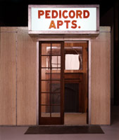 Edward & Nancy Kienholz / 
The Pedicord Apartments, 1982 - 83 / 
Tableau: wood, wallpaper, furniture, doors, carpet, light fixtures, artificial plants, linoleum, floor mats, mirror, fireplace, tape recorders, fluorescent lights, marquee, plants, and polyester resin / 
108 x 192 x 432 in (274.3 x 487.7 x 1,097.3 cm) / 
Collection of the Frederick R. Weisman Art Museum, Minneapolis, MN
