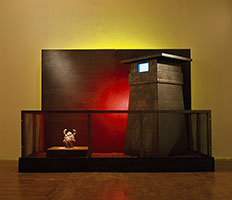 Terry Allen / 
Youth in Asia, 1983 / 
3-dimensional work, sound installation / 
Lead, porcelain, chewing gum, earth, yellow neon, red spotlight, tape recorder, television, speaker, audio cassette, transformer / 
72 x 97 1/2 x 53 in (183 x 248 x 135 cm) / 
Audio cassette: 90'
