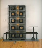 Edward & Nancy Reddin Kienholz / 
The Cage (from The Volksempfängers Series), 1975 / 
box iron, chain-link fencing, galvanized metal, 10 Volksempfänger radios, cloth, one cobblestone tamper, tape player, foot switch, lights, plywood, galvanized sheet metal base / 
75 1/8 x 75 3/4 x 20 in (190.5 x 192.4 x 50.8 cm) / 
Private collection